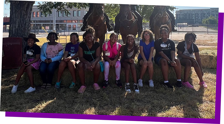 The Fort Worth Mounted Patrol poses on horseback with the group of young leaders for a photo.